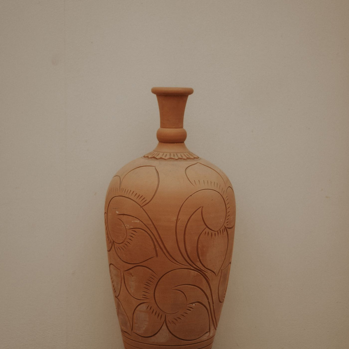 A terracotta vase carved in detail across the surface.