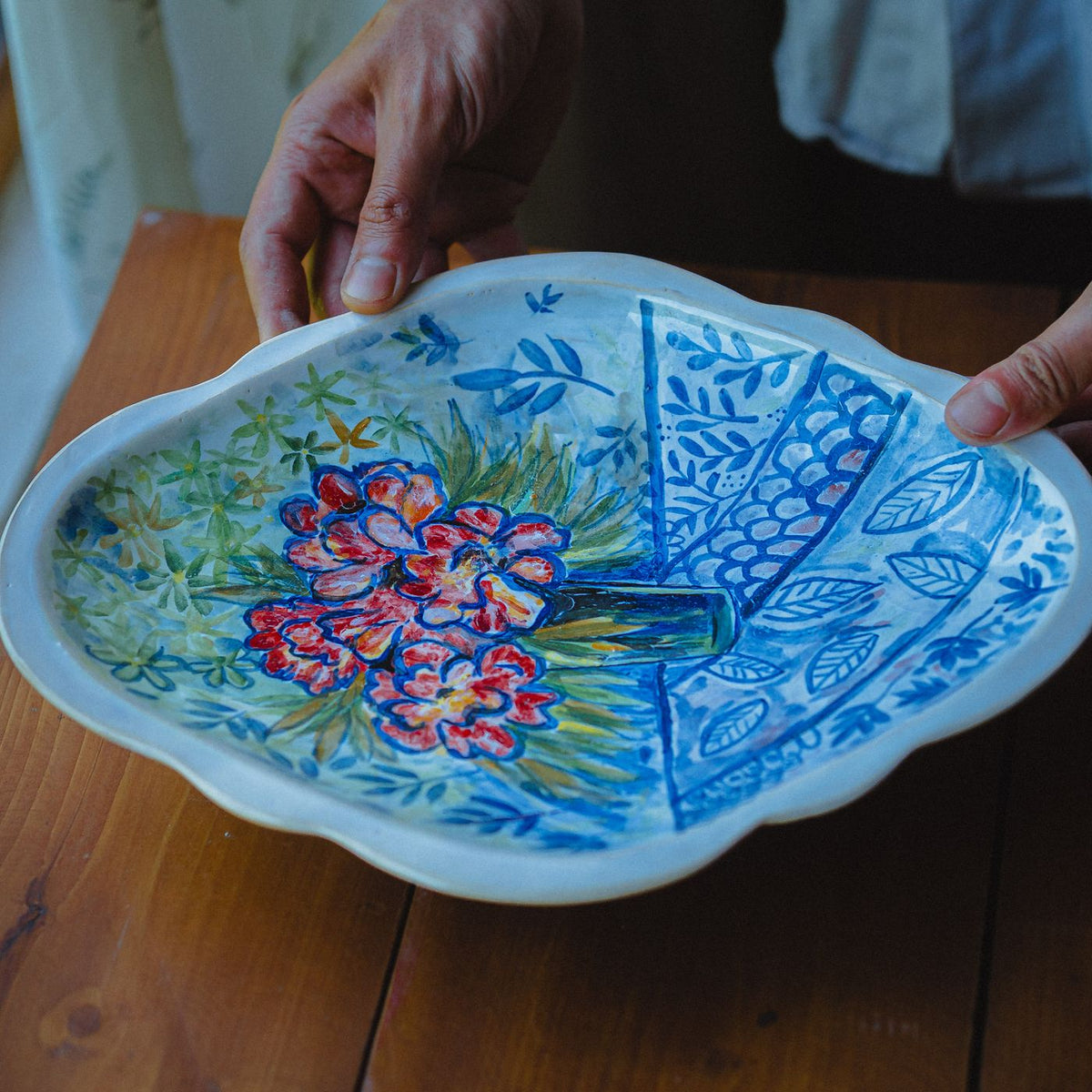 A handmade ceramic plate carrying a floral design.